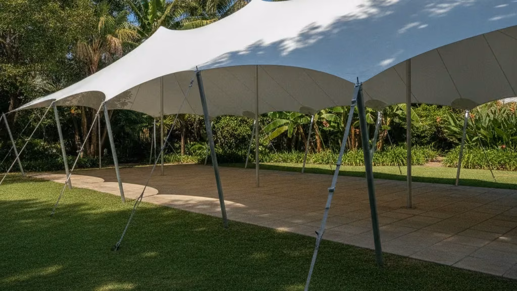 White waterproof stretch tent tensioned in organic curves over a garden and paved patio