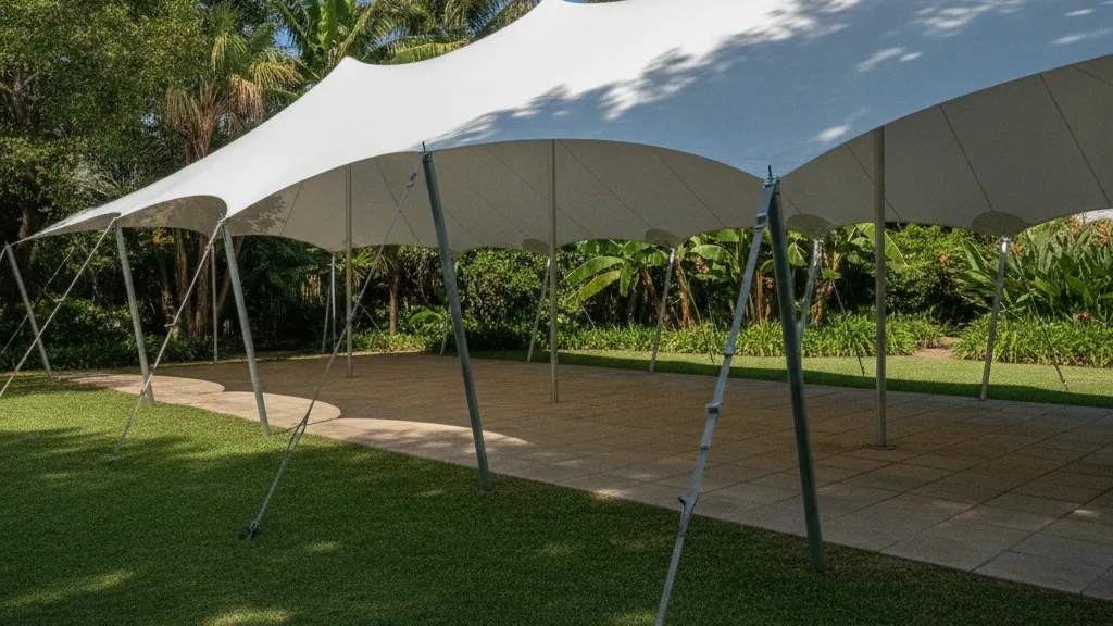 White waterproof stretch tent tensioned in organic curves over a garden and paved patio